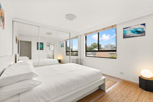 悉尼Large 1-Bed with Swimming Pool in Iconic Bondi的白色卧室设有两张床和大窗户