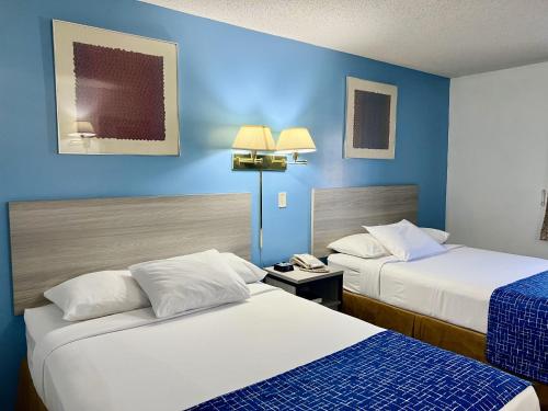赫尔希赫尔希旅程住宿酒店的两张位于酒店客房的床,拥有蓝色的墙壁