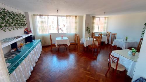 普诺Ayma Hostel Puno的一间设有两张桌子和两张白色桌子的餐厅