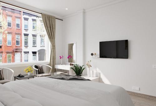 胡志明市Montcalm Hotel Saigon的白色的卧室设有床铺和墙上的电视