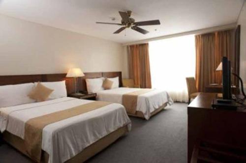 碧瑶A paradise nestled in the City of Pines, Camp John Hay Baguio City的酒店客房配有两张床和吊扇。