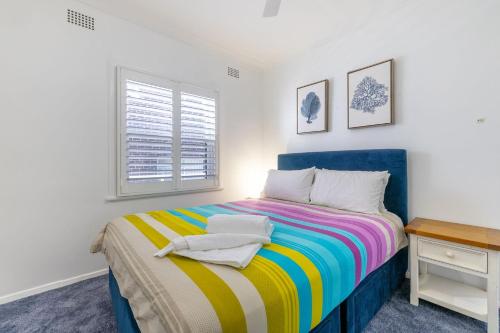 尼尔森湾Bayside, 5 21 Victoria Parade - unbeatable location, with linen and bed making, and air conditioning的一间卧室配有一张床、一张书桌和一个窗户。