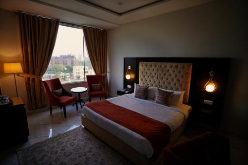 拉合尔Faletti’s Grand MM Alam Road的一间设有大床和窗户的酒店客房