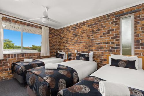 布里斯班杜旺别墅酒店的一间卧室设有三张床和砖墙
