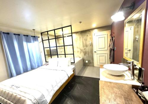 釜山Yeonsan In Hotel的一间卧室配有一张床、一个浴缸和一个水槽