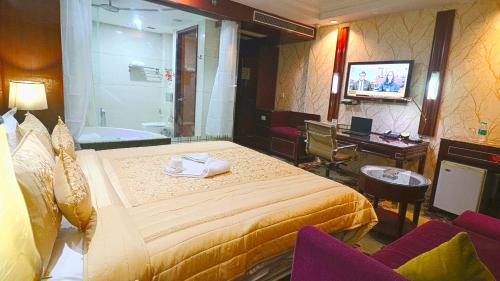 古尔冈SkyCity Hotel Gurgaon的酒店客房设有床、浴缸和电视。