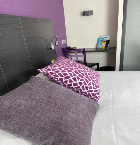 里摩日Kyriad Direct Limoges Nord的床上有紫色和白色枕头