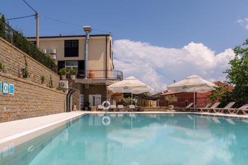 伊佐拉Hotel Stara šola - Oleander Resort的一个带椅子和遮阳伞的大型蓝色游泳池