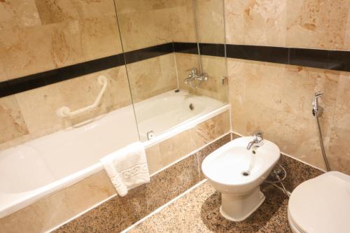 麦纳麦快乐时光酒店的浴室配有卫生间、浴缸和水槽。