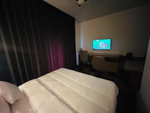 JhirnaEminence The Corbett的酒店客房配有一张床、一张书桌和一台电视。