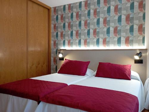 桑亨霍Apartamentos VIDA Sanxenxo的卧室配有带红色枕头的大型白色床
