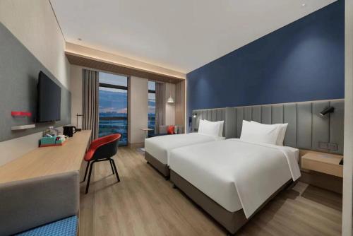长春长春生态广场智选假日酒店的酒店客房设有白色的床和蓝色的墙壁。