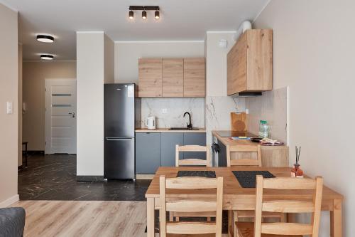 波兹南Poznań Airport Homely Apartment的厨房配有木桌和冰箱。