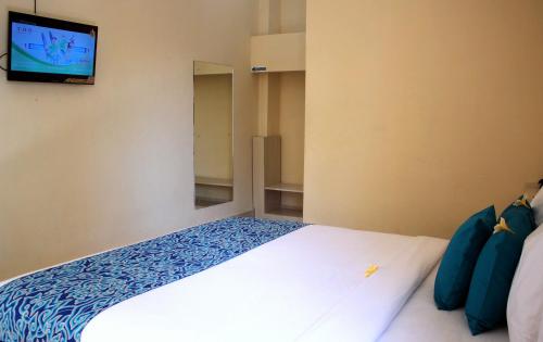 TjakranegaraDjembank Hotel的卧室配有一张床铺,墙上配有电视