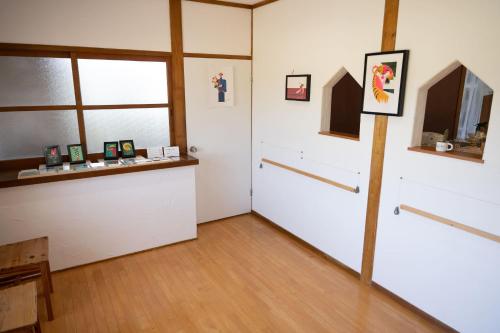 壹岐市ikibase Guest House的一间设有白色门窗和木地板的客房