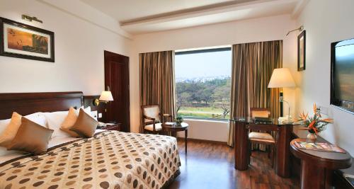 迈索尔Fortune JP Palace, Mysore - Member ITC's Hotel Group的配有一张床、一张书桌和一扇窗户的酒店客房