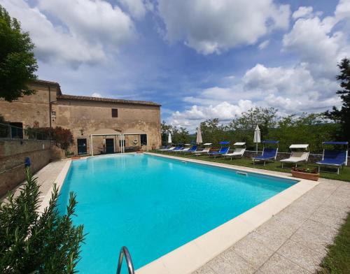 圣焦万尼达索Villa La Consuma : casa storica in paese, giardino, piscina, WiFi的一座带蓝色躺椅的游泳池,位于大楼旁