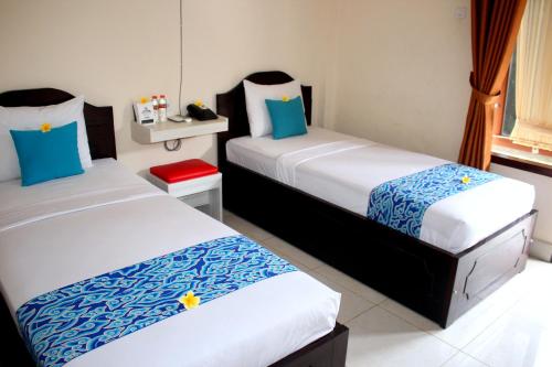 TjakranegaraDjembank Hotel的一间设有两张蓝色和白色床单的房间