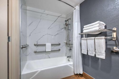 大草原城大草原城速8酒店的带淋浴和白色浴缸的浴室
