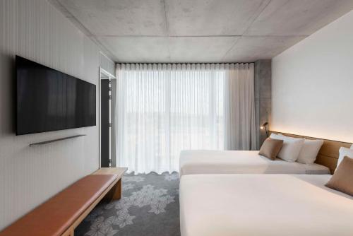 阿德莱德Vibe Hotel Adelaide的酒店客房设有两张床和一台平面电视。