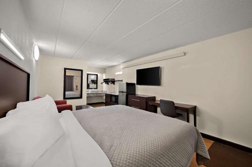 皮奥里亚Suburban Studios Peoria的一间酒店客房,配有一张白色的床和一张书桌