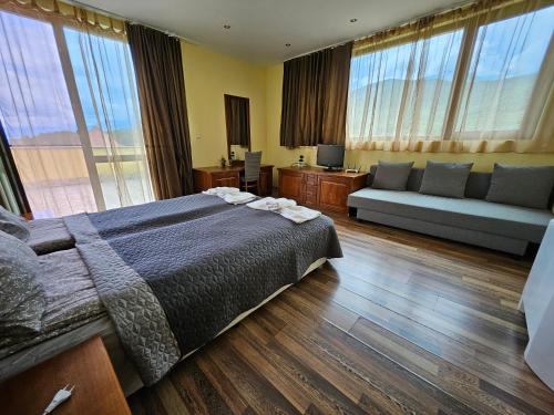 贝尔科维察Family Hotel Komhotel的一间卧室配有一张床、一张沙发和窗户。