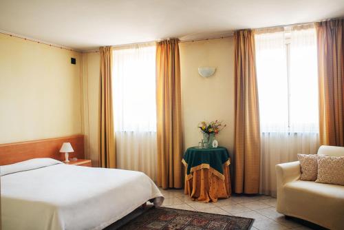 Villanova dʼAstiAlbergo del muletto的一间卧室配有一张床、一把椅子和窗户。