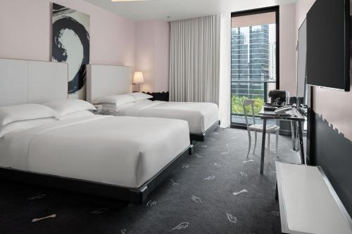 迈阿密DUA Miami, Autograph Collection的酒店客房设有三张床、一张桌子和一台电视。
