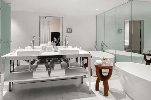 迈阿密DUA Miami, Autograph Collection的浴室配有3个盥洗盆、浴缸和浴缸。