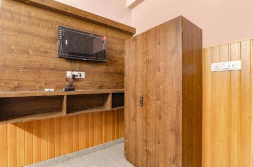 坎普尔Gsv hotel的木墙上配有电视的房间