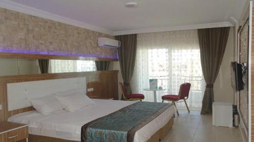 BeyreliPRİNCESS AQUA RESORT & SPA的一间卧室配有一张床、两把椅子和电视