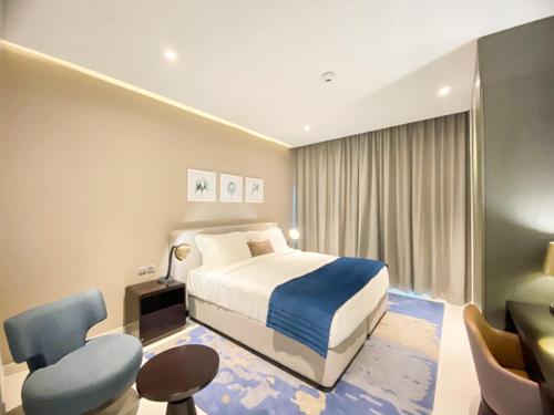 迪拜Comfy 1BR in Damac Maison Prive by Huaxia Homes的配有一张床和一张书桌的酒店客房