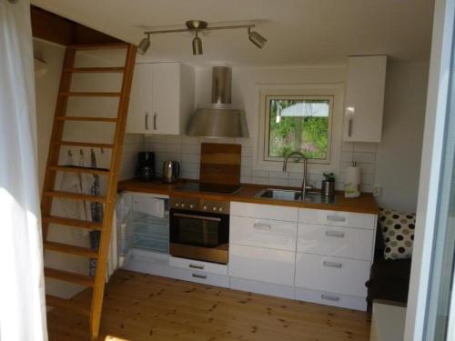 LjugarnKleines Ferienhaus - Tiny house - auf Gotland 700 Meter zum Meer的厨房配有白色橱柜、梯子和水槽