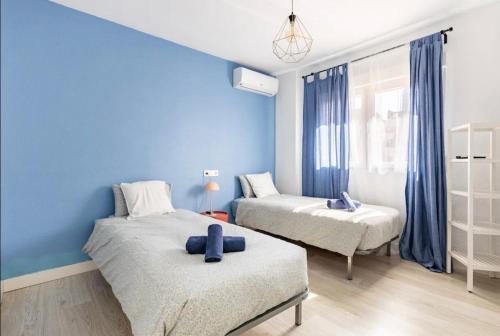卡塔赫纳Apartamentos Duque Cartagena的一间卧室设有两张床和蓝色的墙壁