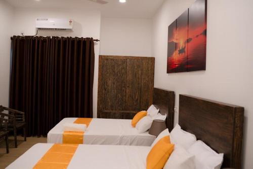 卡图纳耶克Lucky Transit Hotel的一间卧室设有两张床,墙上挂着一幅画