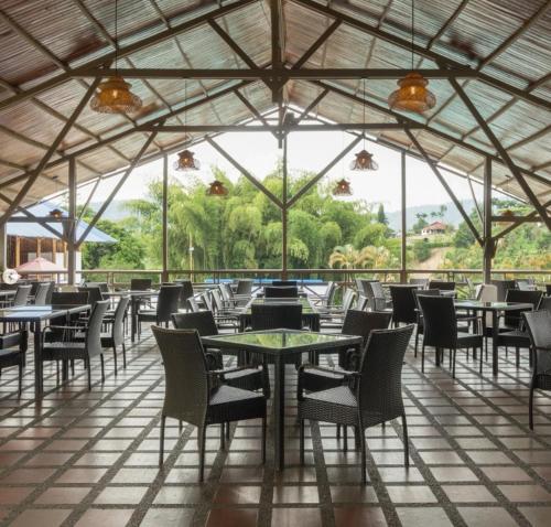 佩雷拉Hotel Villa Mónaco的餐厅设有桌椅和大窗户。
