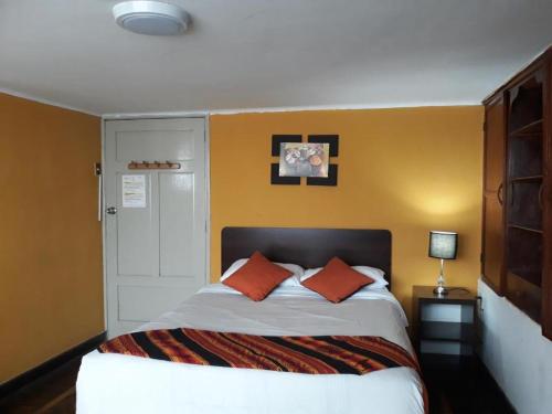 利马Sumaq Wasi Barranco II的一间卧室配有带两个橙色枕头的床