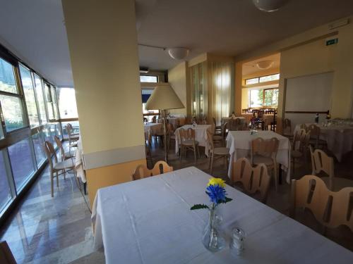 里米尼Hotel Prestige 3 Stars的一间设有桌椅的餐厅和一个花瓶