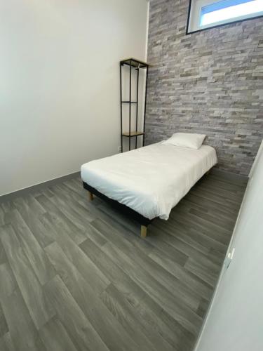 Rouxmesnil-BouteillesAPPARTEL 76 CHAMBRES的一间卧室设有一张床和砖墙