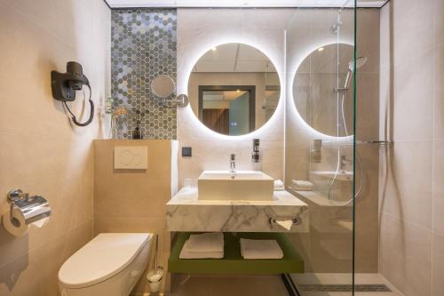 布雷达Leonardo Hotel Breda City Center的一间带卫生间、水槽和镜子的浴室