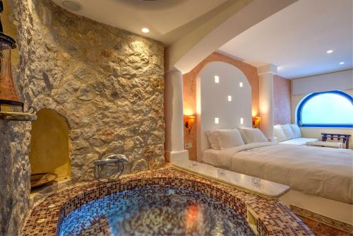 阿克罗蒂里阿斯塔特套房酒店的卧室设有石墙大浴缸