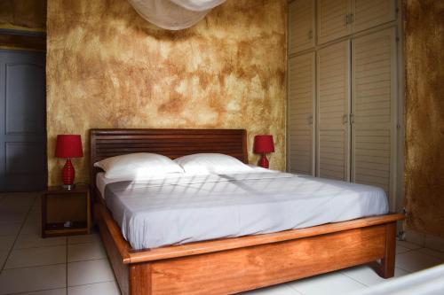 克里比La Villa Lou, Musée Des Arts Grand Batangua的一间卧室配有一张带白色床单和两盏灯的床。