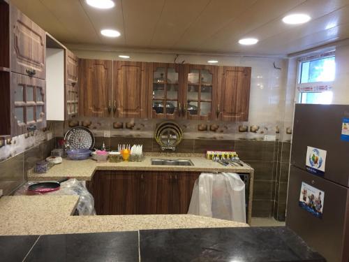 安曼LH HOUSE的厨房配有木制橱柜、水槽和冰箱。
