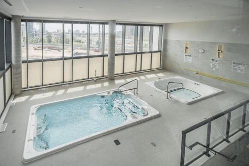 基奇纳Newly Built Condo w Amazing Amenities and Views的大客房设有窗户,配有大浴缸。