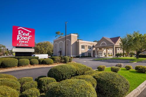 奥尔巴尼Red Roof Inn & Suites Albany, GA的一间有红色屋顶客栈标志和灌木的酒店