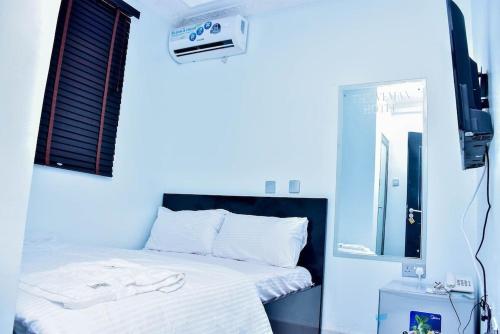 拉各斯THRIVEMAX HOTEL AND SUITE的卧室配有一张带镜子的白色床