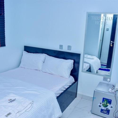 拉各斯THRIVEMAX HOTEL AND SUITE的卧室配有一张带镜子的白色床