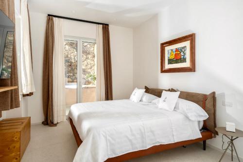 卡普里Le donne di Capri - Charming apartments in Capri的一间卧室配有一张带白色床单的床和一扇窗户。