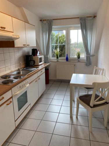 比勒费尔德Ferienhof Kröger的厨房配有白色橱柜、桌子、桌子和微波炉