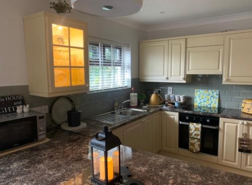 LoughanureIvy Lane的厨房配有白色橱柜和炉灶烤箱。